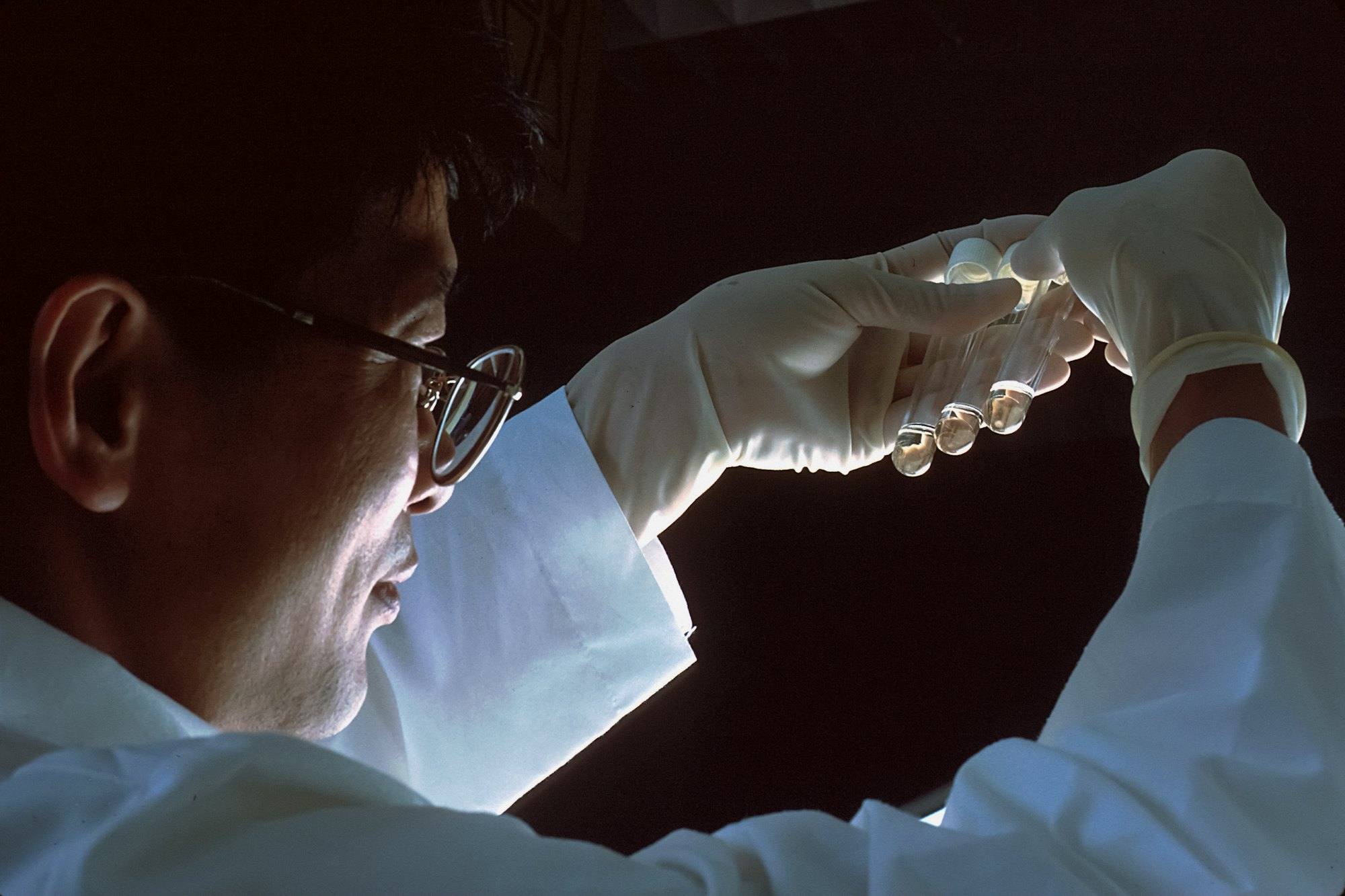 A scientist holding test tubes up to the light