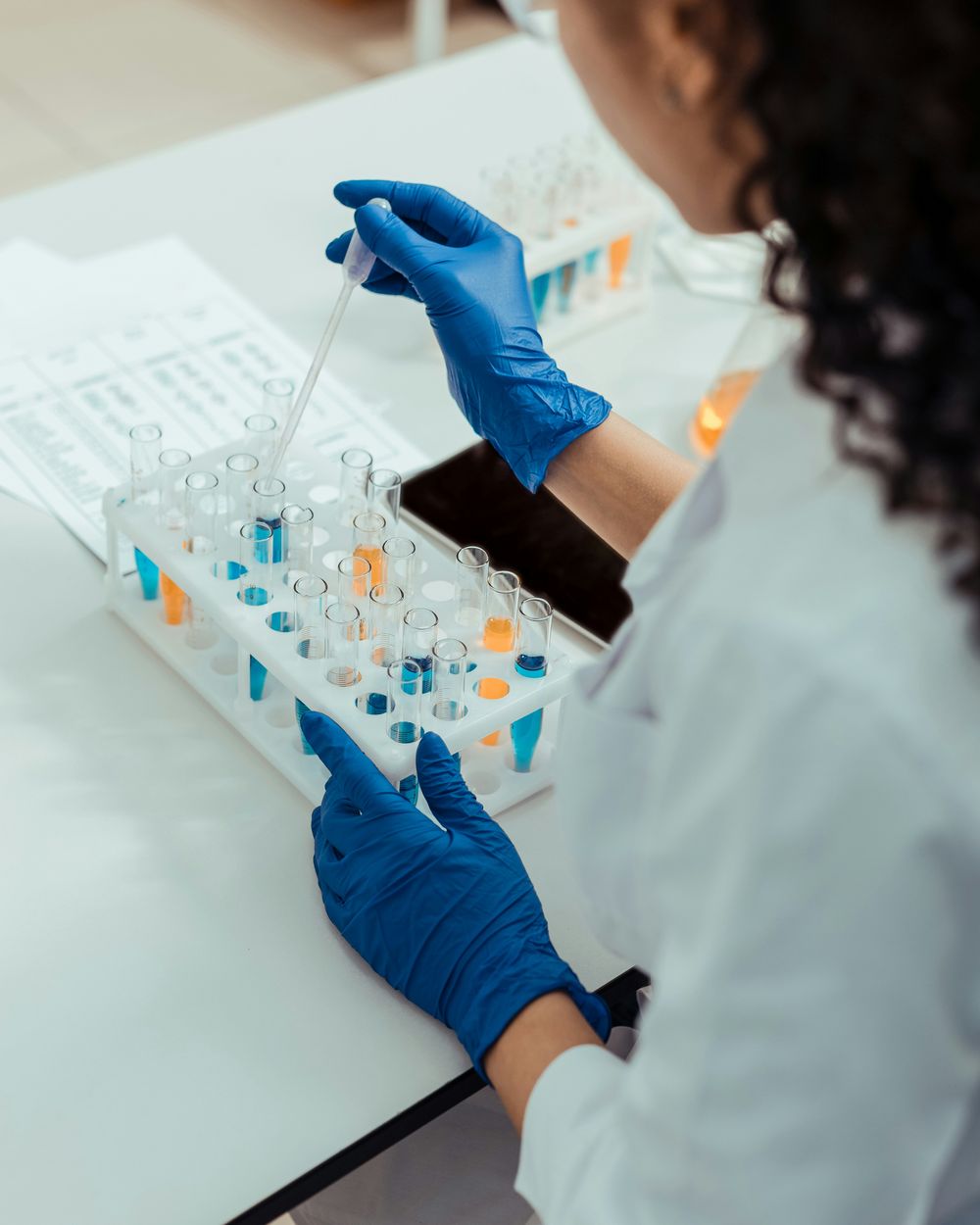 A scientist pipetting samples into a rack of test tubes